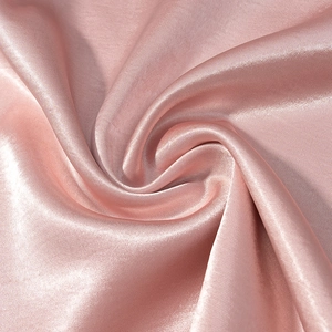Détail du tissu satiné rose montrant sa texture lisse et son élégant drapé brillant