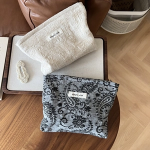 Detail of linen and paisley makeup bags with simple wish label on a wooden tray