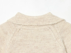 Detail of high neck folding design and raglan sleeve stitching on beige knitted sweater