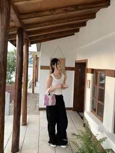 Lifestyle shot of a hand-woven purple and cream cotton macrame bag in a sunny corridor