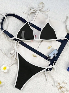 Flat lay of a two-piece bikini with black and white color blocking and side-tie detailing