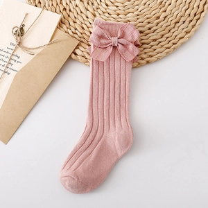 Detail of pink rib-knit baby socks with a large golden striped decorative bow