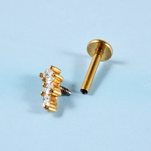 Détail macro d'un labret plaqué or avec trois zircons blancs et filetage interne précis