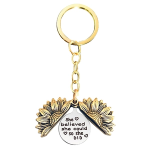 Detail showing an open sunflower keychain with 'She believed she could so she DID' engraving