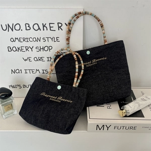 Detail of denim mini handbags featuring gold embroidery and colorful beaded handles