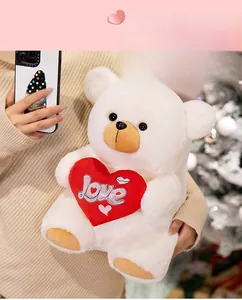 Detail of white plush teddy bear holding a red velvet heart with Love embroidery