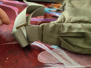Detail of khaki nylon shoulder strap and plastic buckle on lightweight crossbody bag