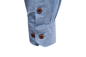 Détail du poignet d'une chemise en lin bleu clair avec trois boutons aspect bois