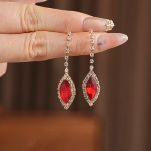 Close-up of golden tassel earrings with red marquise stone and sparkling crystals