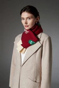 Detailed knit texture of a red Christmas scarf with snowflake patterns and green accents