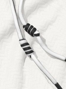 Macro view of woven black and white drawstring cord on a textured jacquard hoodie fabric