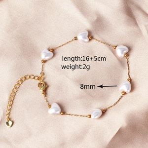 Detailed view of gold pearl bracelet on silk with 16+5cm length and 8mm heart charms