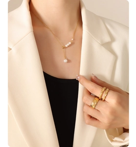 Detail of elegant gold necklace with pearls and matching quilted rings on a female model