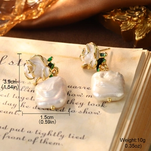 Detailed view of vintage rose earrings with baroque pearls on retro book pages
