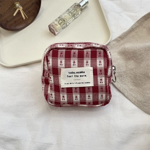 Close-up of red checkered fabric pouch with a zipper closure and minimalist cloth label