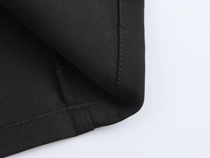 Close-up of black trench coat fabric showing premium texture and fine stitching detail