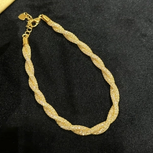 Close-up of golden money bag pendant bracelet with sparkling cubic zirconia on black velvet