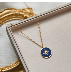 Macro view of blue enamel ocean star compass pendant on a gold plated chain