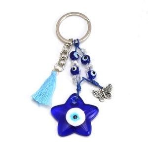 Macro detail of evil eye keychain with blue tassels, star pendant and silver butterfly