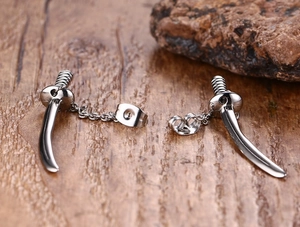 Detail view of silver punk katana sword earrings with chains on a wooden surface