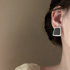 Close-up of geometric resin stud earrings with silver metal frame on a model