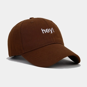 Close-up of white hey embroidery on a dark brown cotton twill baseball cap with curved brim