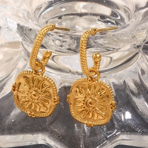 Macro detail of 18K gold-plated hoop earrings featuring vintage sun relief medallions