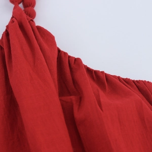 Détail de robe en lin rouge montrant les bretelles nouées et l'encolure plissée