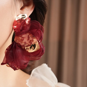 Close-up of deep wine red chiffon flower earring with golden metallic center on model