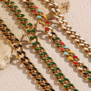 Detail view of colorful oil-dripped Cuban link chains on a textured stone surface