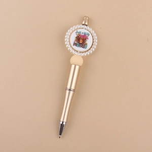 Close-up of golden beaded pen featuring a cartoon highland cow and Moody text detail