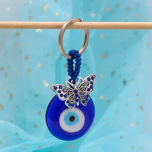 Detail showing blue evil eye keychain with silver butterfly charm and braided rope