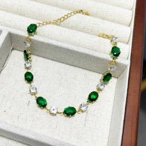 Gros plan sur les pierres ovales vert émeraude et les zircons sur un bracelet doré