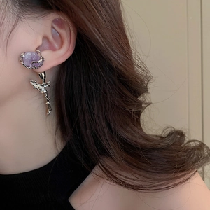 Detail of rose silver earring featuring a purple crystal and intricate metal wing pendant