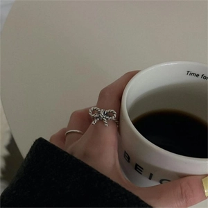 Detail of vintage 925 silver bow ring with twisted texture worn in a lifestyle setting