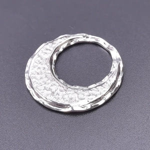 Macro shot of silver hammer-textured stainless steel pendant with wavy irregular edges