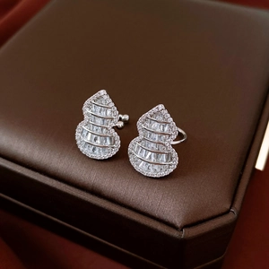 Macro shot of silver gourd earrings with zircon pave setting on a brown leather surface