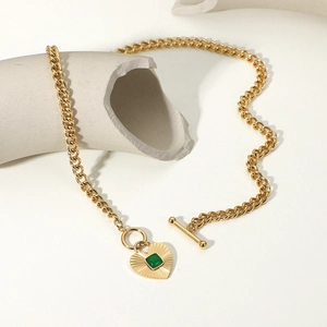 Gold heart pendant necklace with green agate and OT toggle clasp on artistic white ceramic