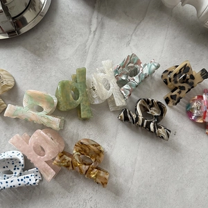 Flat lay of diverse acetate hair claws in leopard, amber, and floral patterns on stone