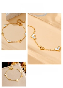 Detailed view of gold plated chain bracelet with shell inlay and hollow heart pendants