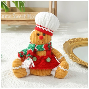Detail of a plush gingerbread man chef doll with a red skirt and knit scarf