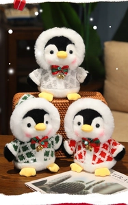 Close-up of three plush penguin dolls with winter hoods and bells in a cozy gift basket