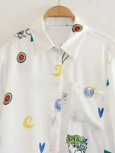 Détail de chemise blanche avec imprimés abstraits de soleil et lune sur cintre en bois