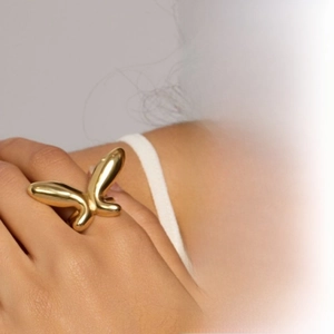Detailed close-up of a 316 stainless steel butterfly open ring with a gold mirror finish