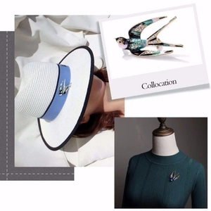 Dettagli della spilla a rondine in smalto con cristalli su cappello e maglione