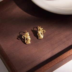 Gold cat earrings with white zircon on wooden base, elegant feline silhouette jewelry