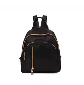 Front view of black waterproof nylon mini backpack with gold zippers and vertical pocket