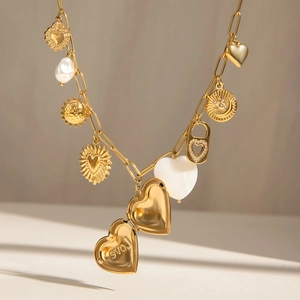 Collier en acier doré avec médaillon cœur, perles et breloques soleil sur fond blanc