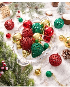 Close-up of red, green and gold Christmas ornaments on a white mirror tray with snow