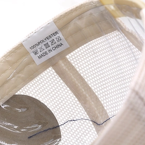 Close-up of the 100% polyester fabric care label inside a beige mesh trucker cap